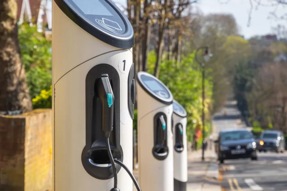 Row of curbside electric vehicle chargers with black car approaching in background